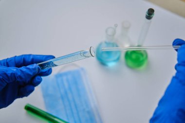 Laboratuvarda cam çubuk ve tüp tutan bilim adamı, yakın plan. Çözüm kimyası. Antivirüs çözeltisi