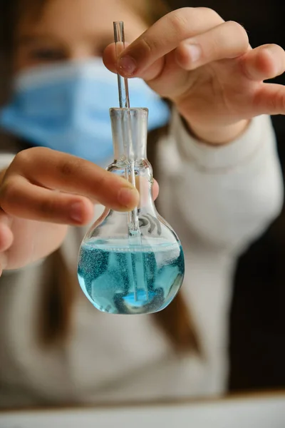 Uma criança brincando de médico com frasco de vidro e líquidos coloridos. Educação e experiências escolares — Fotografia de Stock