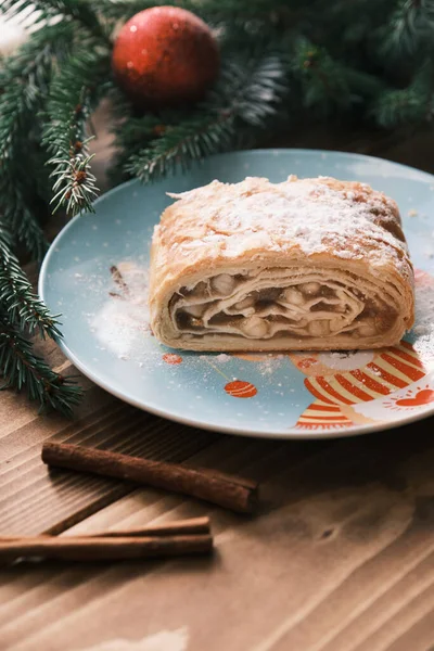 Feche de um strudel em uma chapa de Natal perto de paus de canela. Café da manhã Natal — Fotografia de Stock