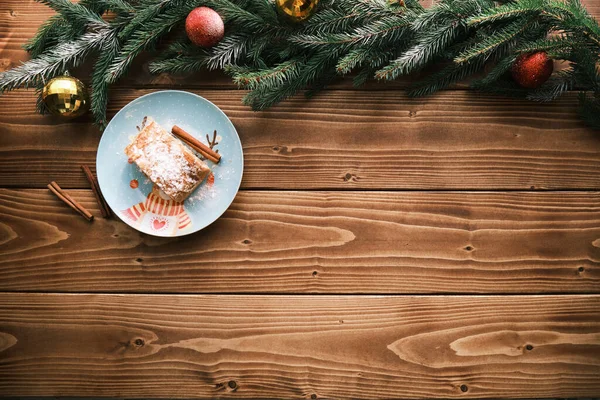Top view of a strudel on a Christmas plate near cinnamon sticks. Christmas breakfast and Christmas tree — Stock Photo, Image