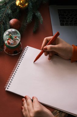 Merkez ofisteki kadın Noel 'de Noel Baba' ya mektup yazıyor. Kar küresi ve dizüstü bilgisayar yakınlarda 