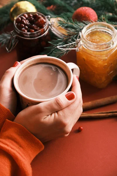 Primeros planos manos femeninas sosteniendo chocolate caliente cerca de tarros de mermelada. Dulce desayuno mañana de Navidad —  Fotos de Stock