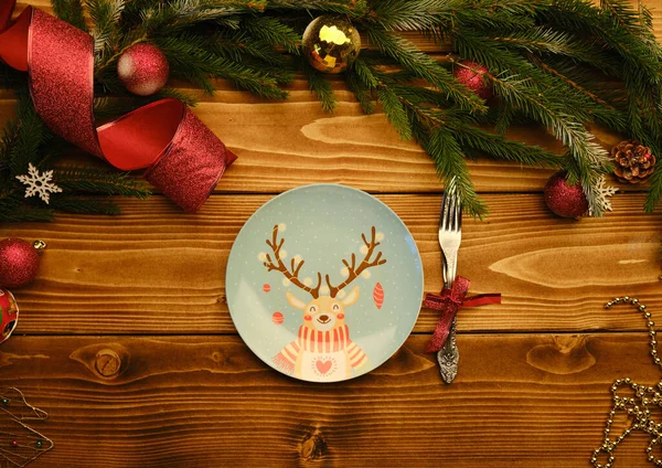 Placa de veado de Natal com garfo e faca em um fundo de madeira com árvore de natal e brinquedos — Fotografia de Stock