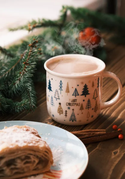 Primer plano de un strudel en un plato de Navidad cerca de palitos de canela y chocolate caliente. Desayuno de Navidad —  Fotos de Stock