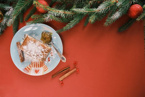 Ovanifrån av en strudel på en jultallrik nära kanel pinnar. Julfrukost och julgran Royaltyfria Stockbilder
