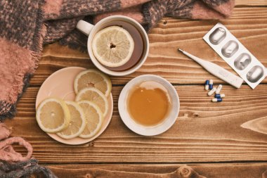 Grip limonu ve bal için doğal ilaçlar. Tahta masa termometresi ve haplarla sıcak çay. 