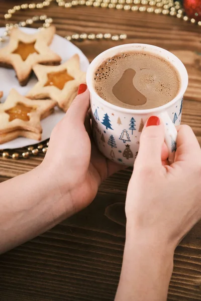 Taza de mano femenina de chocolate caliente o chocolate con sobre mesa de madera con galletas de jengibre y decoración navideña —  Fotos de Stock