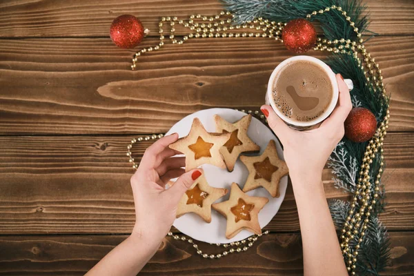 Taza de mano femenina de chocolate caliente o chocolate con sobre mesa de madera con galletas de jengibre y decoración navideña —  Fotos de Stock
