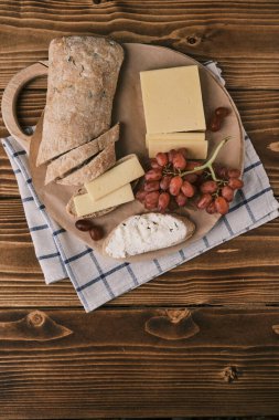 Ciabatta, üzüm ve peynirli ahşap bir tahtanın üst manzarası. Krem peynirle dilimlenmiş.