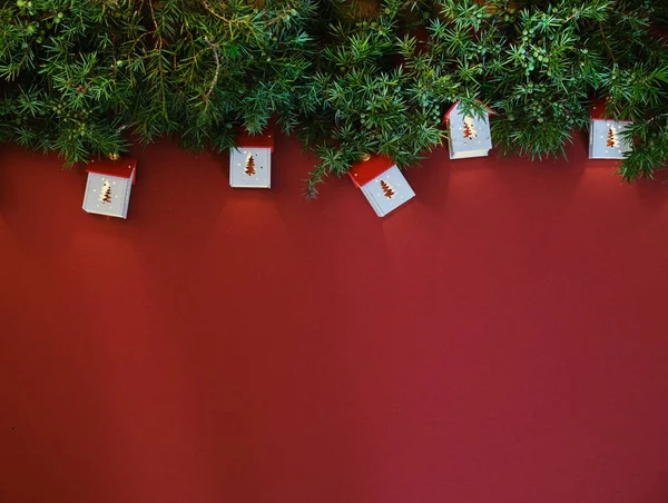 Leksakshus och furu grenar med gåva på röd bakgrund. Stockfoto
