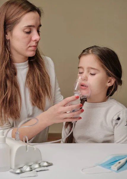 Matka w masce pomaga córce w masce inhalacyjnej. Koncepcja lekarza dziecięcego. Wdychanie — Zdjęcie stockowe