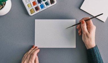 Temiz beyaz bir kağıtta fırça tutan bir kadın. Mesajlaşma raddesi. Resim ve sanat hobisi