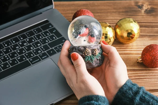 Pendekatan Snow Globe Snow Flakes dan burung di tangan, Beautiful Holiday Concept dengan mainan Natal. Bekerja di rumah — Stok Foto