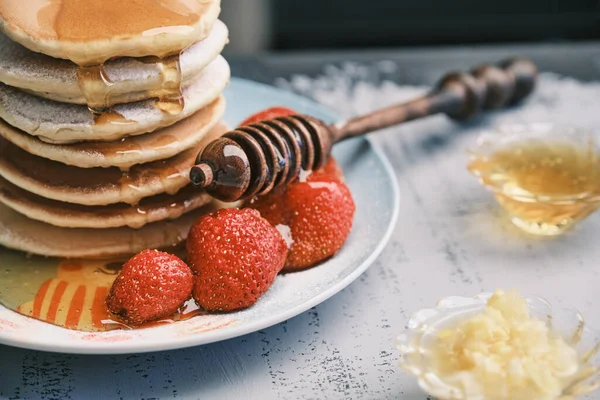Hot pancakes with honey on a plate. Delicious dish for breakfast. Honey flows down from a wooden stick on a dish. Homemade food — Stock Photo, Image