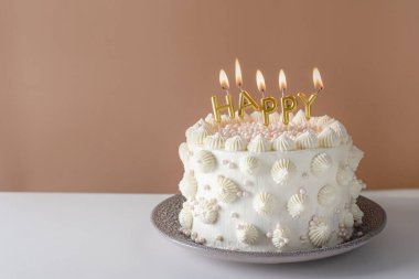 Bej arka planda beyaz pasta ve mumlar. Mumlu doğum günü pastası. Metin için yer