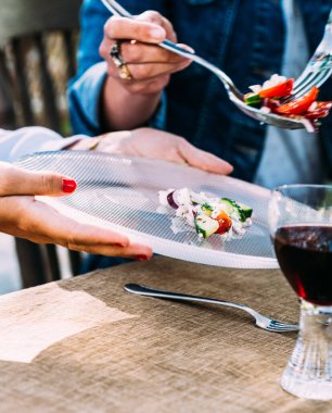 Anne çocuğunun tabağında salata servisi yapıyor güneşli bir bahçe ortamında. Yüksek kalite fotoğraf
