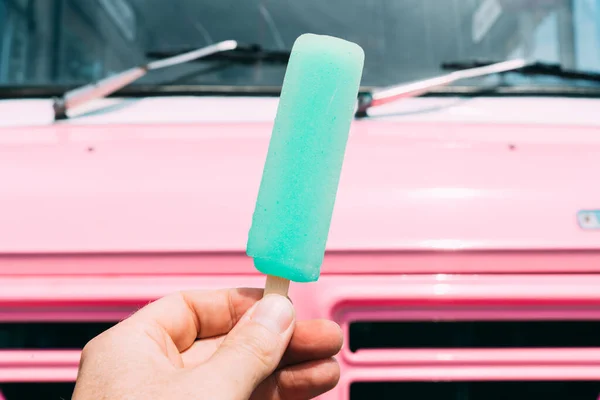 Arka planda pembe dondurma kamyonu ya da minibüsü olan pastel mavisi dondurma. Yüksek kalite fotoğraf. Pov atışı. Bakış açısı.