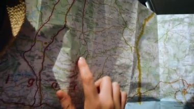 Bir kadın eli ile bir arabanın içindeki bir yol haritasının bakış açısı.