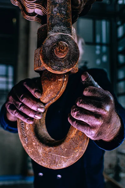 Workers hand with big industrial pulley hook, dirty hands. Industrial. Moody.