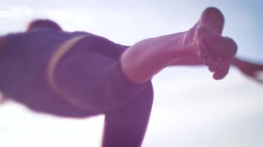 Gün doğumunda kum tepelerinde yoga yapan bir kadının silueti. 4K yavaş çekim. Işıklar ve güneş parlıyor.