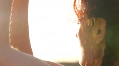 Gün doğumunda kum tepelerinde yoga yapan bir kadının silueti. 4K yavaş çekim. Işıklar ve güneş parlıyor.