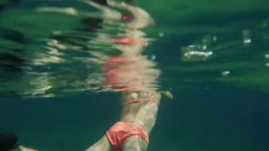 Açık denizde yüzen ve suyun altına dalan bir kız.