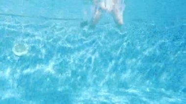 Bikinili genç bir kız yüzme havuzuna dalıyor. Suyun altında. Yaz tatili eğlencesi.