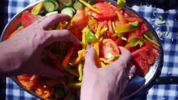 Manos masculinas mezclando una colorida ensalada griega bajo el sol del verano. — Vídeo de stock