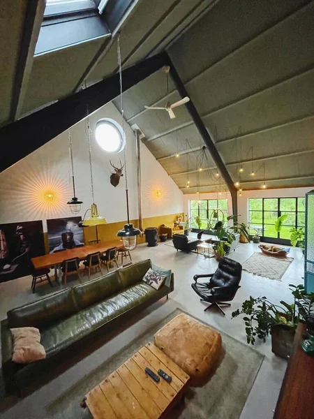 Interieur van een loft. Woonkamer met moderne meubels uit de middeleeuwen. Betonnen vloer en planten. Mosterd gele stoel. Rotan stoel ophangen. Vintage tapijt. — Stockfoto