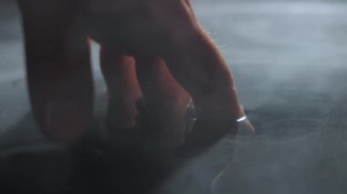 Hand with fingers touching the water surface. Smoke flowing over the water. Slow-motion 180 fps shot. Mythical. The four elements