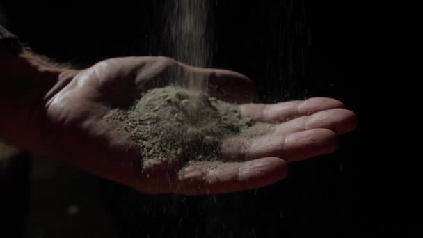 Sand falling into the hand of a male. Black background. Slow-motion 180 fps. The four elements. — Stock Video
