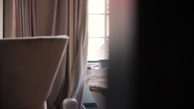 Beyaz köpüklü kadın bacakları bir otel odasında güneş ışığıyla pencereye vuruyor. Lüks ve refah. 180 fps yavaş çekim