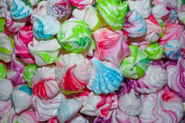 Pembe, açık pembe, menekşe, yeşil, mavi, kırmızı renklerde Meringues öpücüklerinin yakın görüntüsü. Ev yapımı kremalı kurabiyeler. Arkaplan 