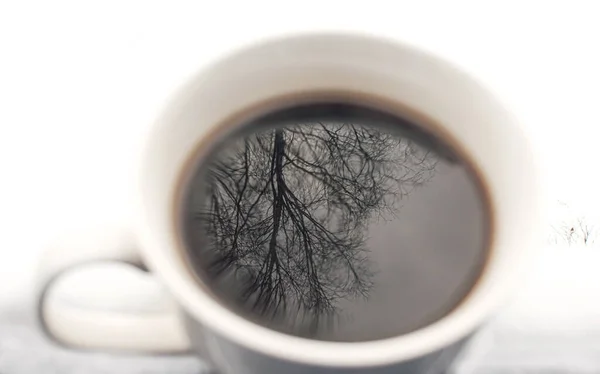 Pohon Merefleksikan Dalam Secangkir Kopi Pada Latar Belakang Bersalju Putih — Stok Foto