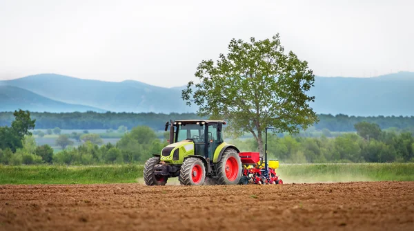 Traktor sprüht Feld im Frühling. — Stockfoto