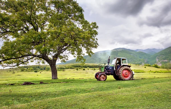 Old rusty tractor with storm weather in the background — Stock Photo, Image