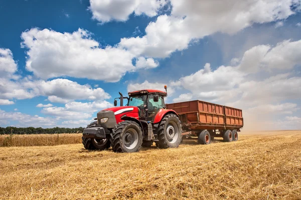 Moderna röda traktorn på jordbruksområdet solig sommardag — Stockfoto