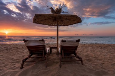 Arkadan görünüşü iki şezlonglar, şezlong kum şemsiyesi altında Sun