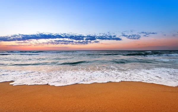 Colorido océano playa amanecer con cielo azul profundo y rayos de sol. —  Fotos de Stock