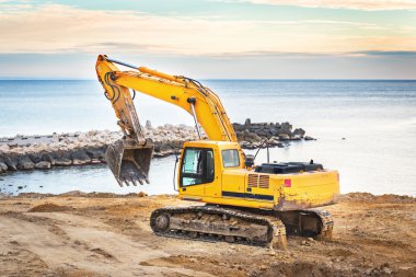 Ekskavatör yükleyici makine günbatımı arka plan ile.