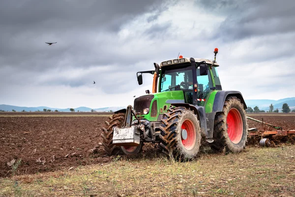 Grüner Traktor und dramatischer Himmel. — Stockfoto