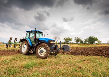 Mavi traktör ve dramatik gökyüzü.