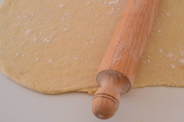 Yuvarlanmış hamurun üstünde merdane var.