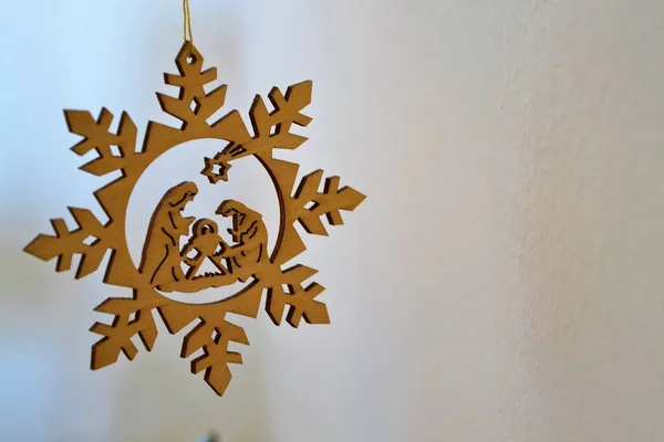 Wieszanie Drewnianej Ozdoby Świątecznej Przedstawiającej Szopkę Wewnątrz Płatka Śniegu — Zdjęcie stockowe