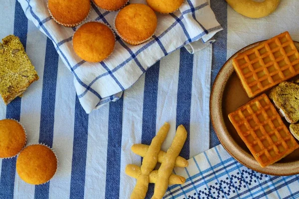 Table set with white and blue mattresses of different patterns with an assortment of high-carbohydrate baked goods: muffins, bread and waffles
