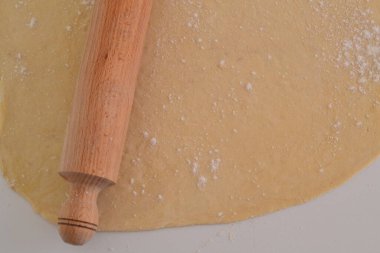 Yuvarlanmış hamurun üstünde merdane var.