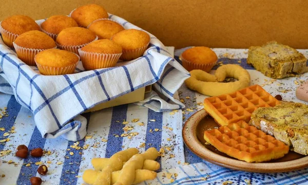 Table set with white and blue mattresses of different patterns with an assortment of high-carbohydrate baked goods: muffins, bread and waffles