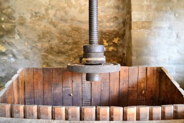 Taş bir duvarın önündeki eski ahşap şarap barajı.