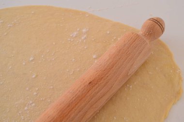 Yuvarlanmış hamurun üstünde merdane var.