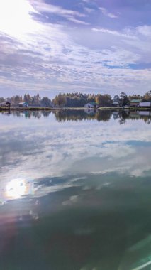 Mükemmel gölde güneşli bir gün. Suda yansıması olan sonbahar gölü. Güneşli bir günde bulutlu bir gökyüzü.
